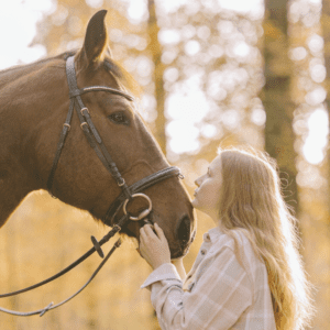 Blonde Frau kuschelt Pferd mit Trense