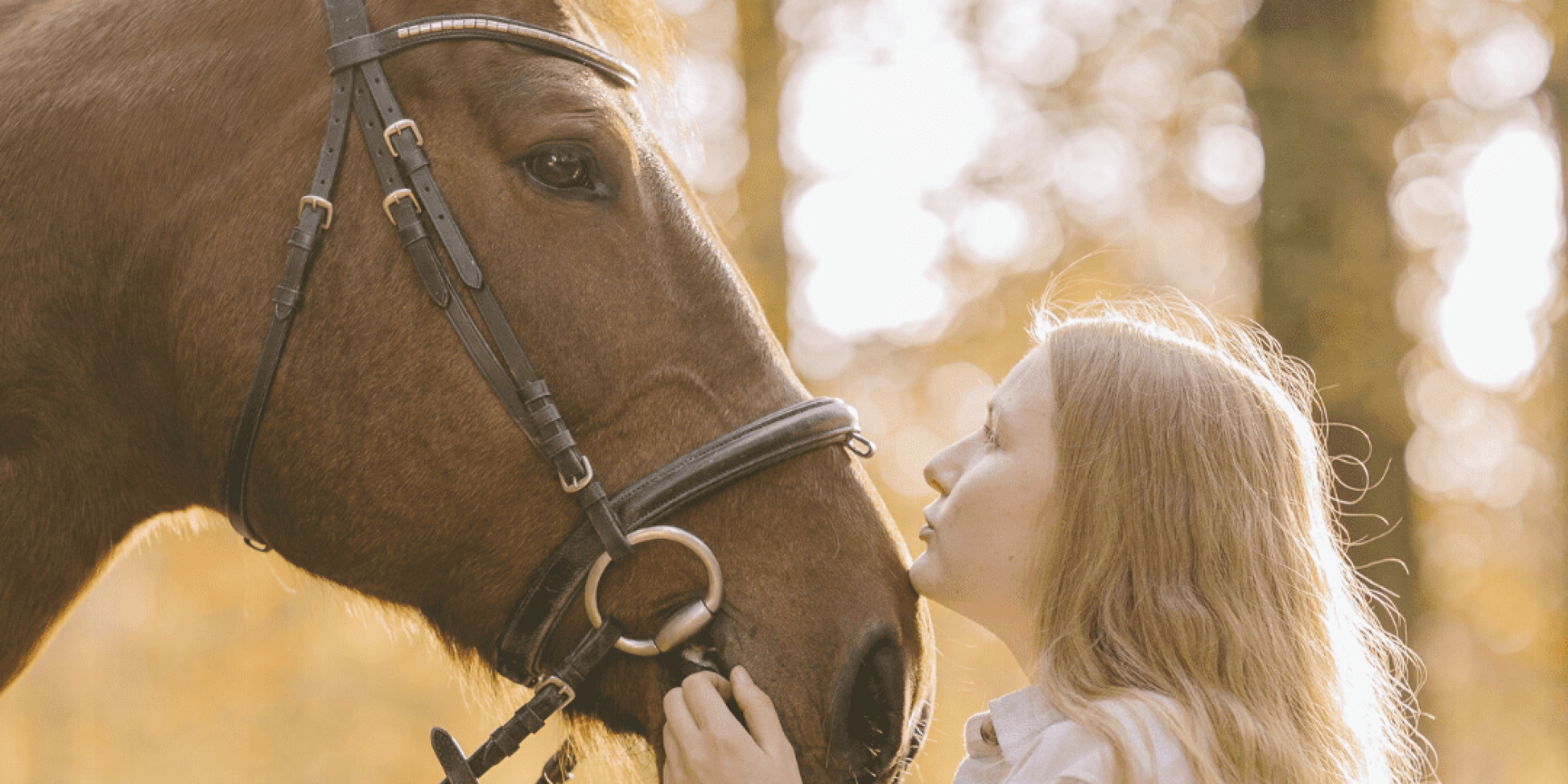 Blonde Frau kuschelt Pferd mit Trense